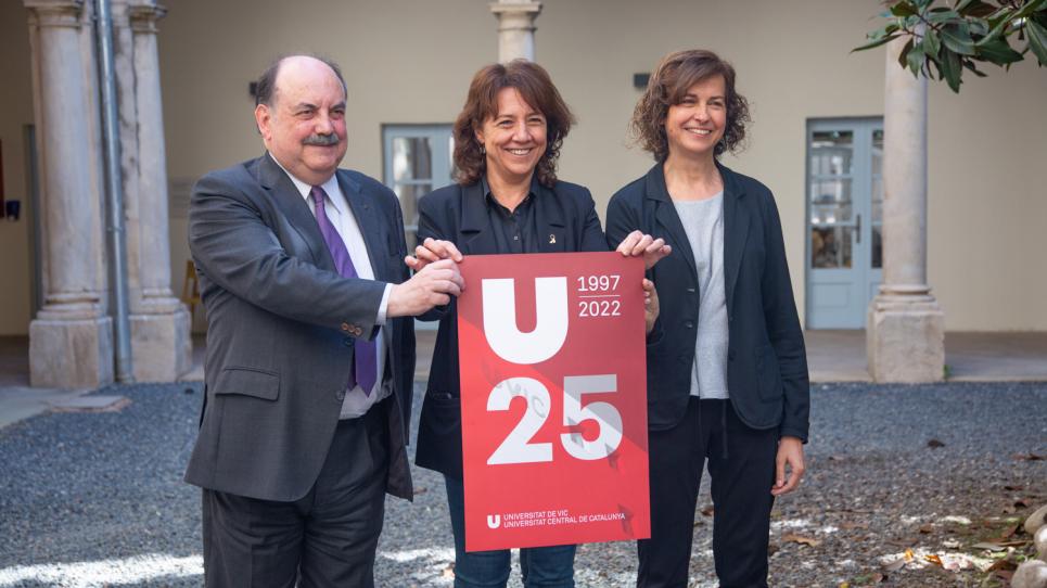 Baños, Erra i Sabata, amb el cartell dels 25 anys de la UVic-UCC