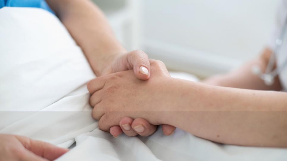 Una mà d'una infermera agafant la mà d'un pacient